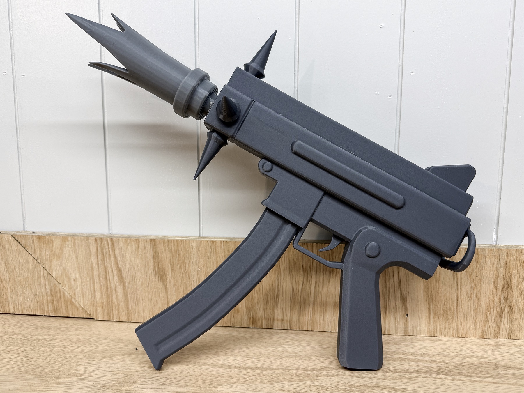 Left-side view of an assembled gray 3D-printed cosplay prop with a curved magazine and flame-shaped muzzle.