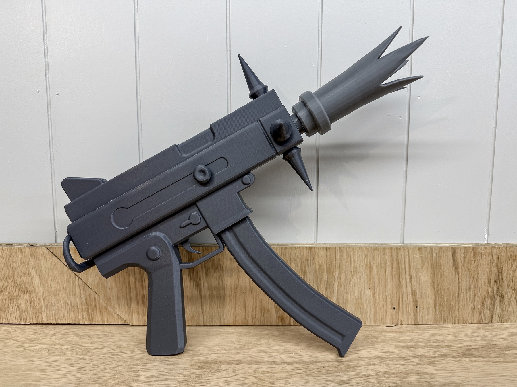 Right-side view of the assembled gray PLA prop resting against a light wall.